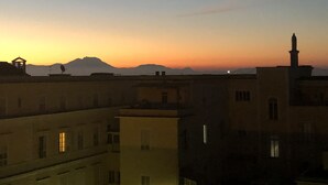 A cityscape at sunset with buildings silhouetted against the sky. - Specchio di Parthenope (Naples)