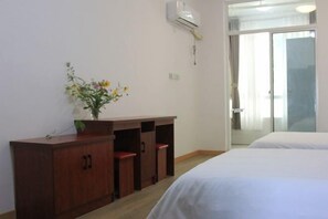 Une chambre d’hôtel avec un bureau en bois, un vase de fleurs, un lit et une porte-fenêtre coulissante donnant sur l’extérieur.