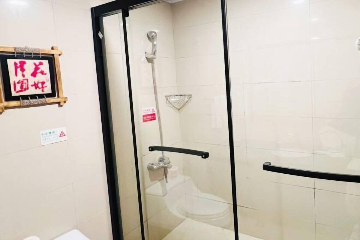 Une cabine de douche fermée par des parois en verre, dotée d’un pommeau de douche à main, de toilettes et d’un porte-serviettes.