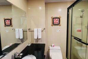 Une salle de bain comprenant des toilettes, un lavabo, un miroir et une douche à parois de verre.