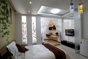 Un dormitorio moderno con cama, escritorio y televisor.