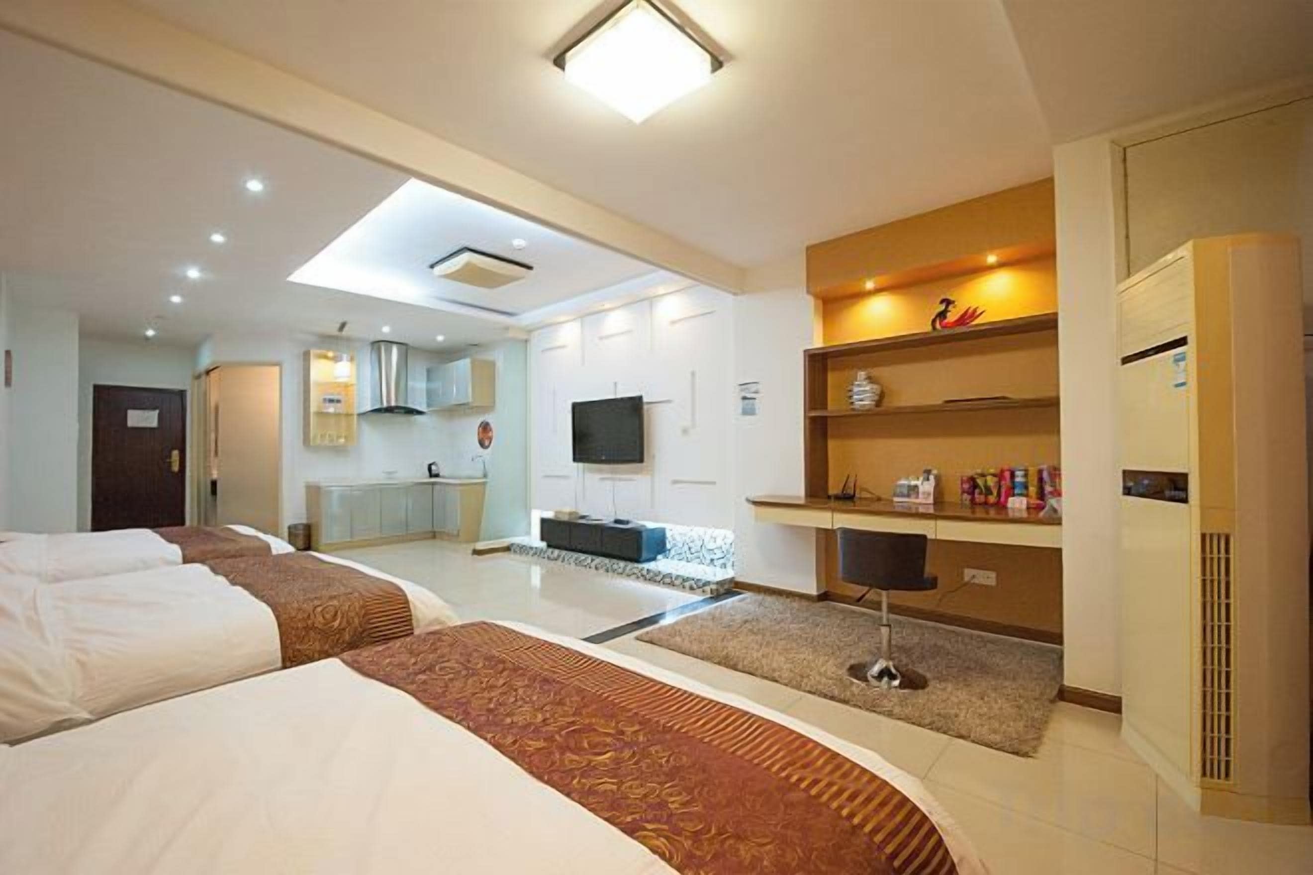 A hotel room with two beds, a kitchenette, a television, and a minibar.