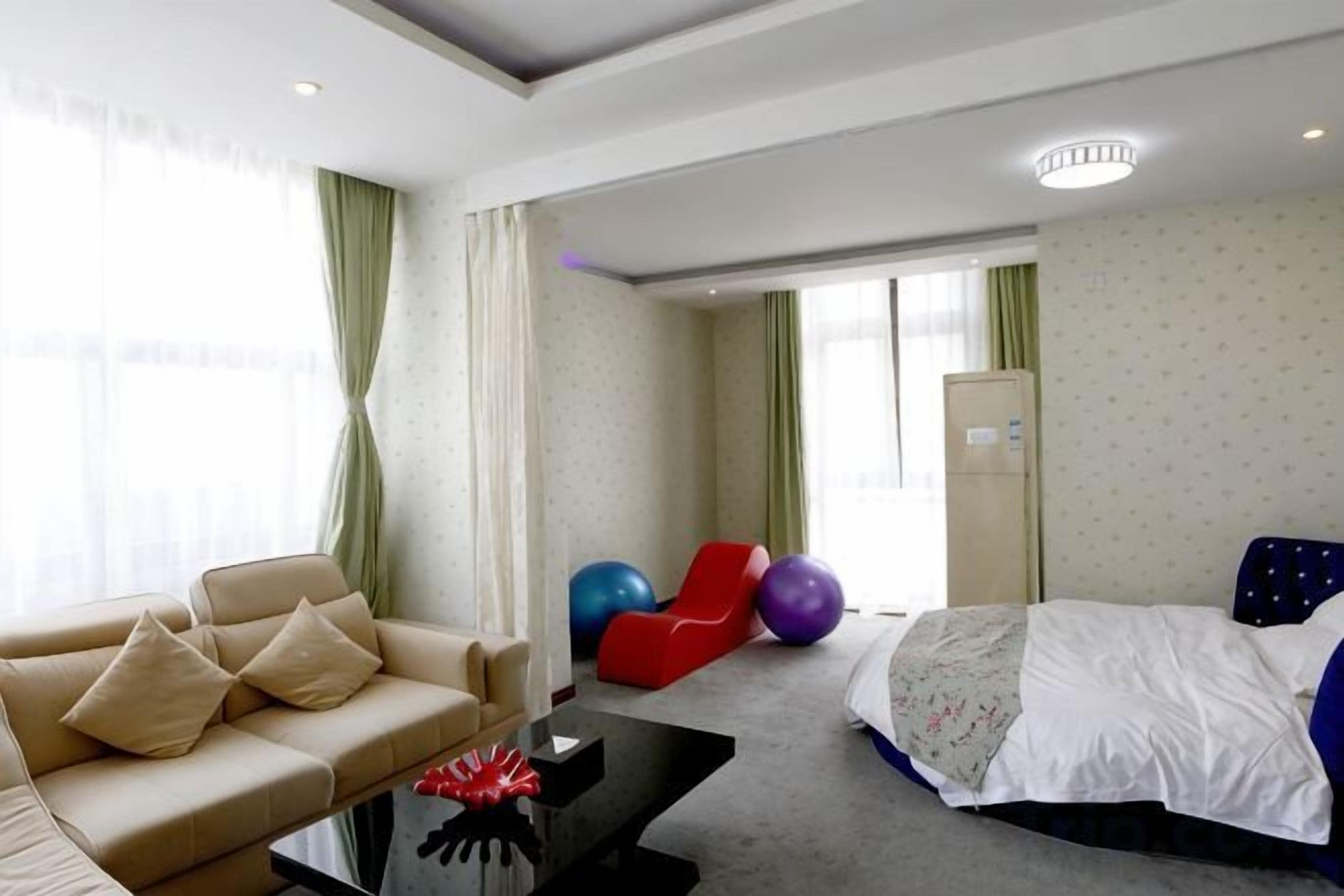 A hotel room with a bed, a sofa, a coffee table, and exercise balls.