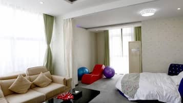 A hotel room with a bed, a sofa, a coffee table, and exercise balls.