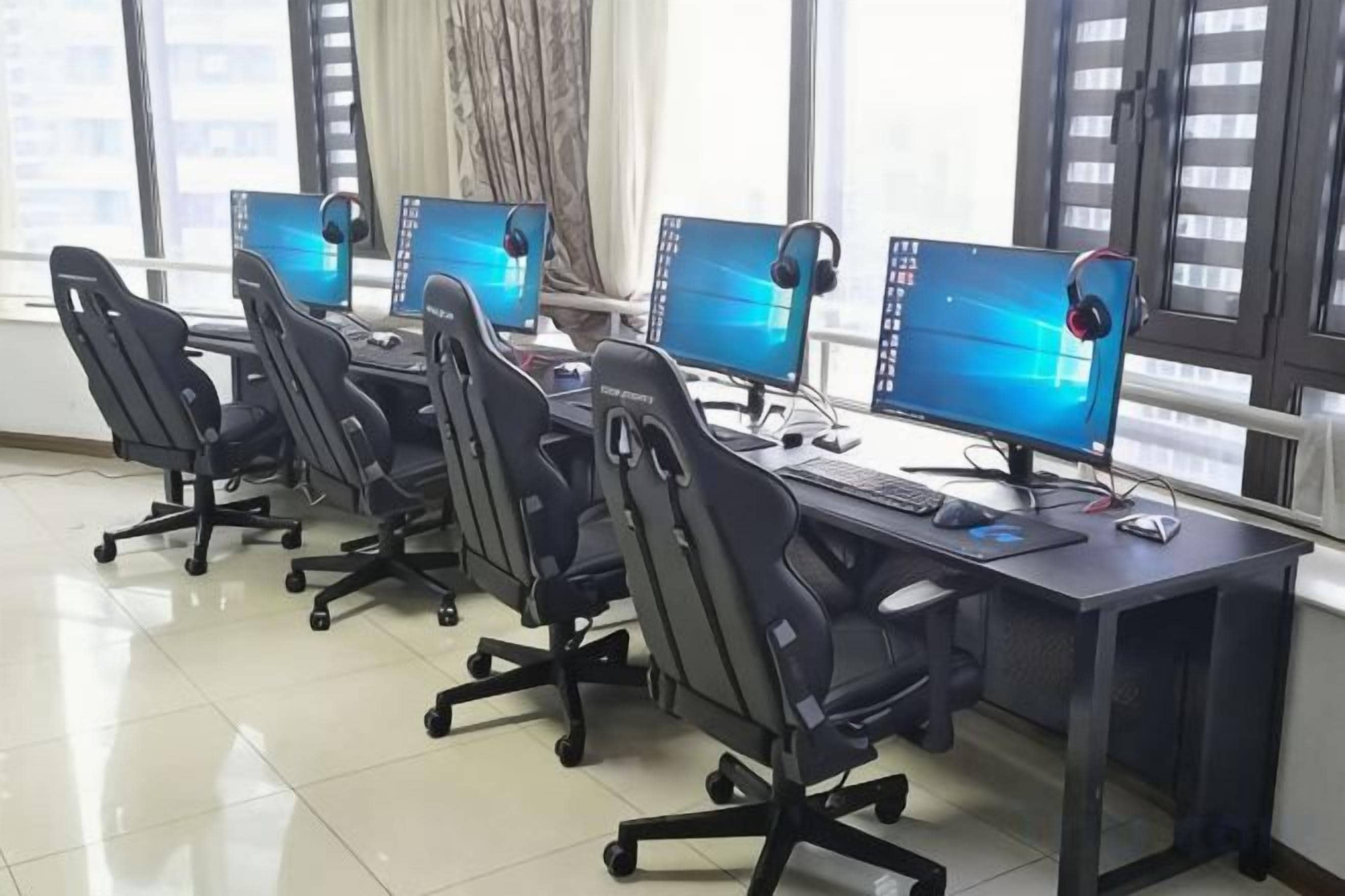 Un laboratorio de computadoras con múltiples estaciones de trabajo, cada una con monitor, teclado y auriculares.