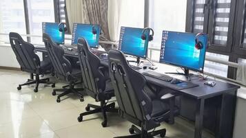 Un laboratorio de computadoras con múltiples estaciones de trabajo, cada una con monitor, teclado y auriculares.