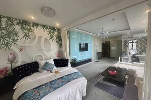 Moderni hotellihuone, jossa on sänky, sohva, sohvapöytä ja televisio.