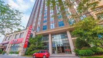 A modern building with a prominent entrance, large windows, and a red car parked in front.
