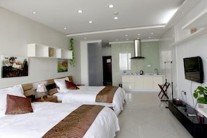 Una habitación de hotel moderna con dos camas, una kitchenette y un televisor.
