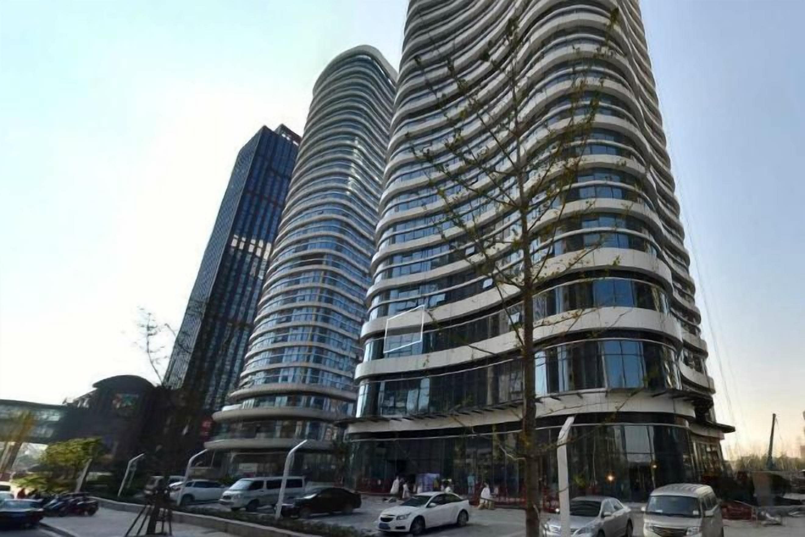 A modern high-rise building with multiple balconies and a curved facade.