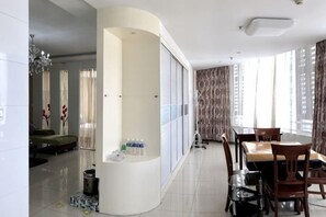 Een hotelkamer met een gebogen witte scheiding, een eettafel met stoelen, een bank en een kitchenette.