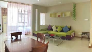 A living room with a green sofa, a wooden dining table, and a coffee table.