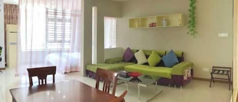 A living room with a green sofa, a wooden dining table, and a coffee table.