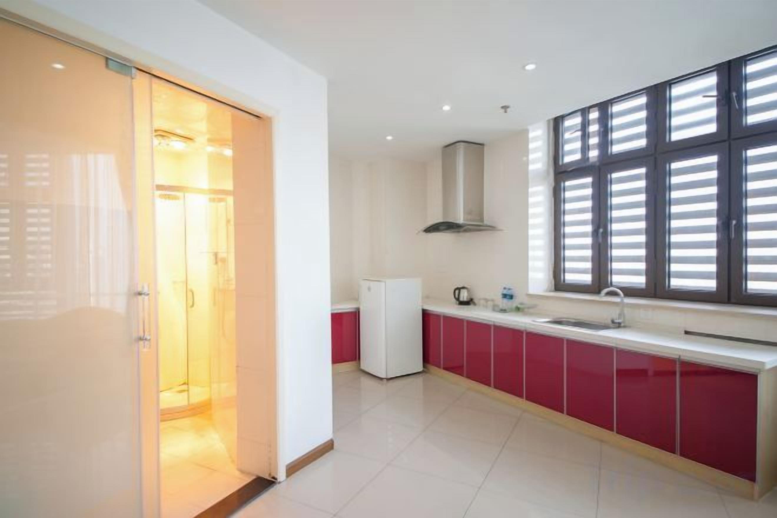 A modern kitchen with a sliding door entrance, a built-in oven, and a window with blinds.