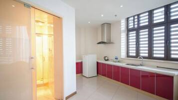 A modern kitchen with a sliding door entrance, a built-in oven, and a window with blinds.