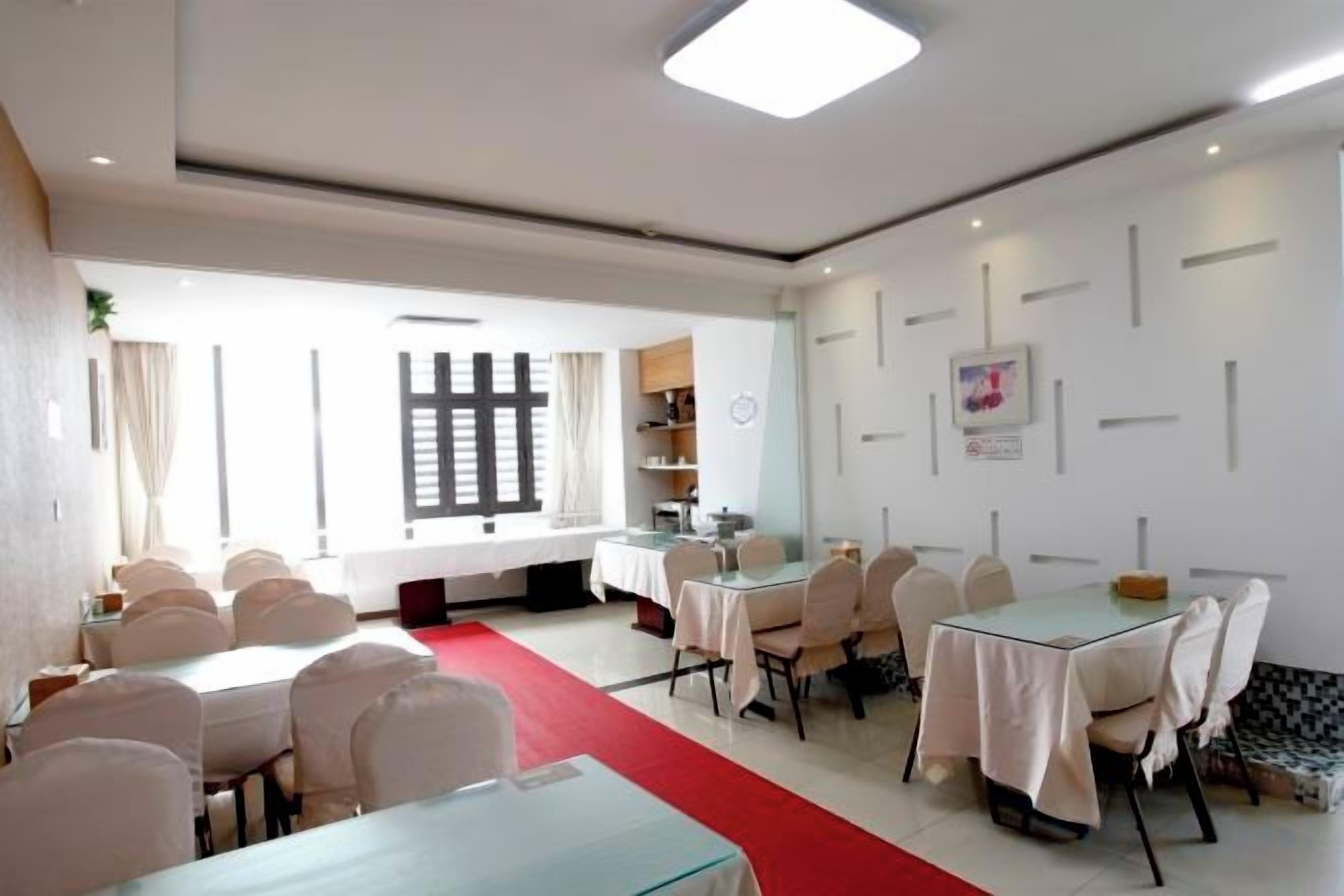 Un comedor de hotel con mesas redondas, sillas y alfombra roja.