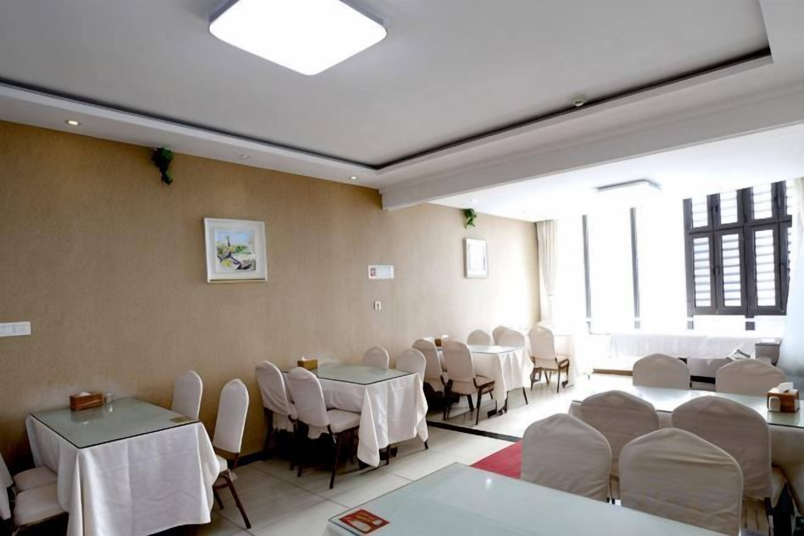 Un salón de conferencias con varias mesas y sillas, ventanas amplias y obras de arte enmarcadas en las paredes.