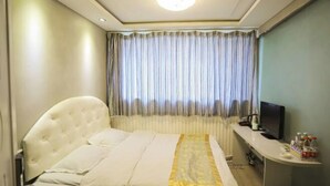 A hotel room with a bed, a desk with a television, and a window with curtains. - Shell Chain Hotel (Mudanjiang North Railway Station Guangsha Branch) (Mudanjiang)