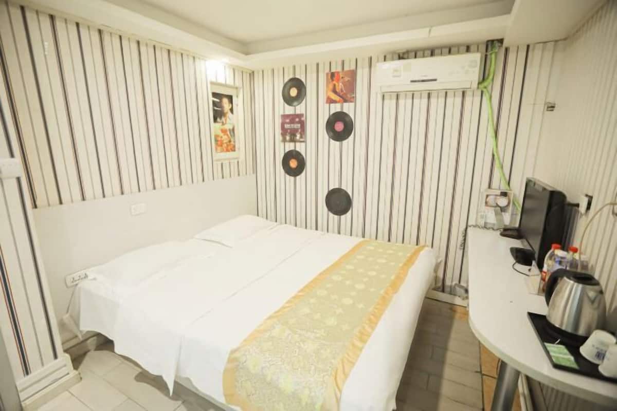 Une chambre d’hôtel comprenant un lit, un bureau avec un ordinateur et des éléments de décoration murale, notamment des disques vinyle.