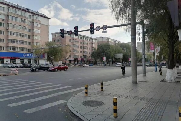 A street intersection with traffic lights, a crosswalk, and buildings in the background.