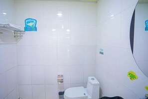 A small, white-tiled bathroom with a toilet, a towel rack, and a soap dispenser. - Shell Chain Hotel (Mudanjiang North Railway Station Guangsha Branch) (Mudanjiang)