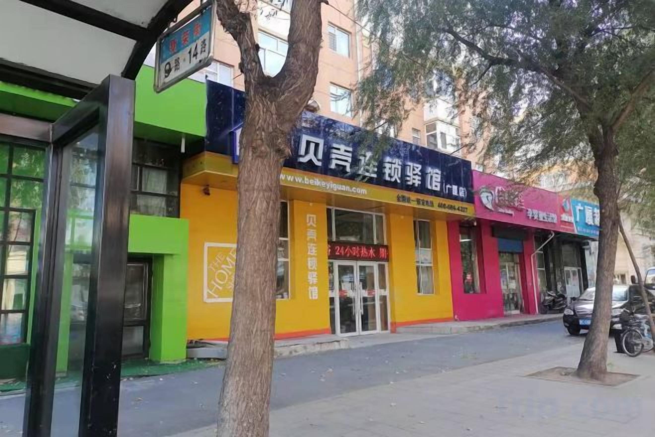 Un edificio con escaparate, un letrero y un árbol en la fachada.