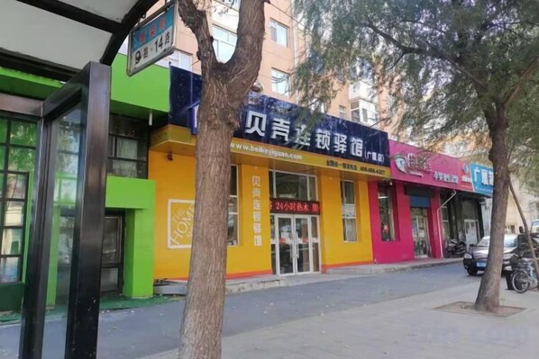 A building with a storefront, a signboard, and a tree in front.