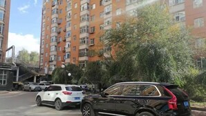 A multi-story residential building with balconies, parked cars, and a clear sky. - Shell Chain Hotel (Mudanjiang North Railway Station Guangsha Branch) (Mudanjiang)