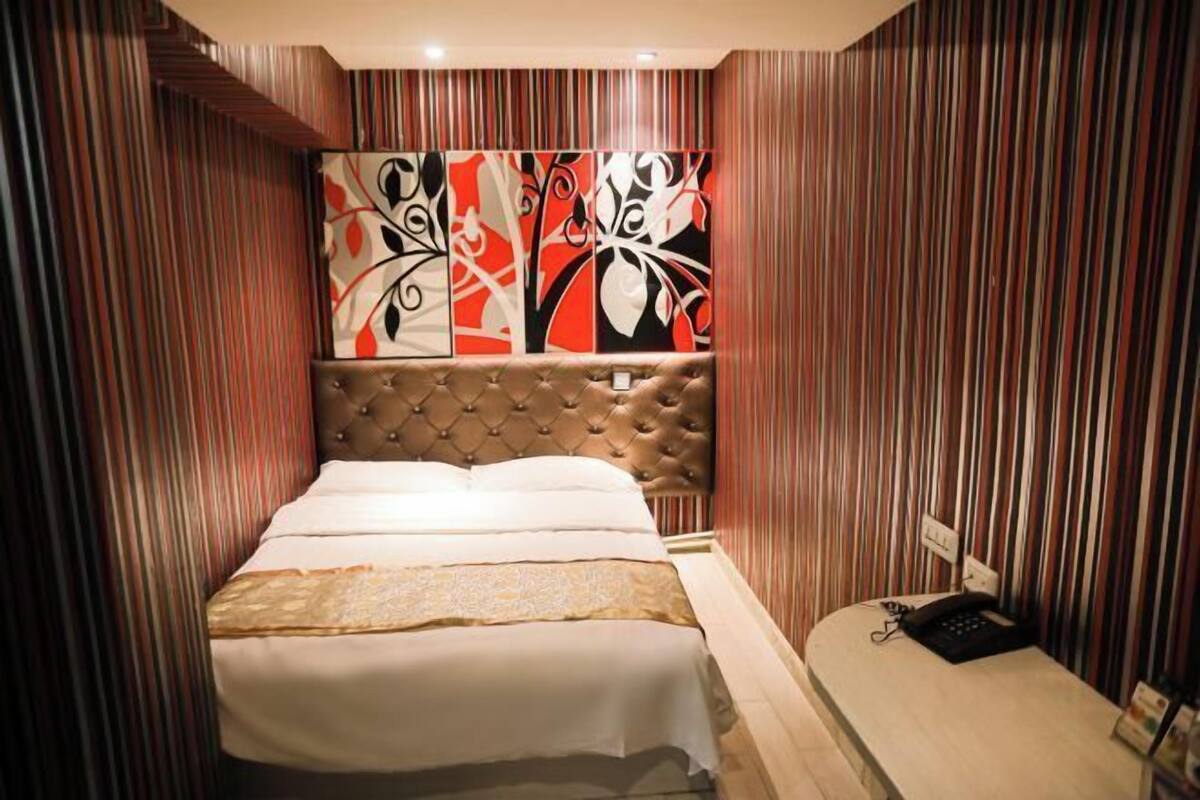 Une chambre d’hôtel avec un grand lit, une tête de lit et un panneau décoratif mural.