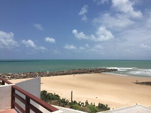 A beach with a rocky shoreline, clear sky, and calm sea. - Hotel Paraiso Natal (Natal)
