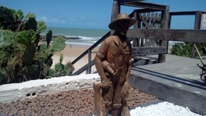 A beach scene with a wooden structure, a cactus, and the ocean in the background. - Hotel Paraiso Natal (Natal)