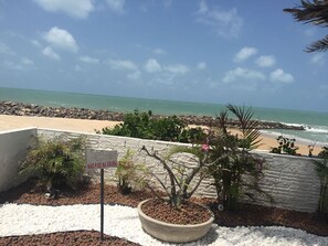 A beach view with a sign that reads 'NÃO PISE NA GRAÇA' and a potted plant in the foreground. - Hotel Paraiso Natal (Natal)