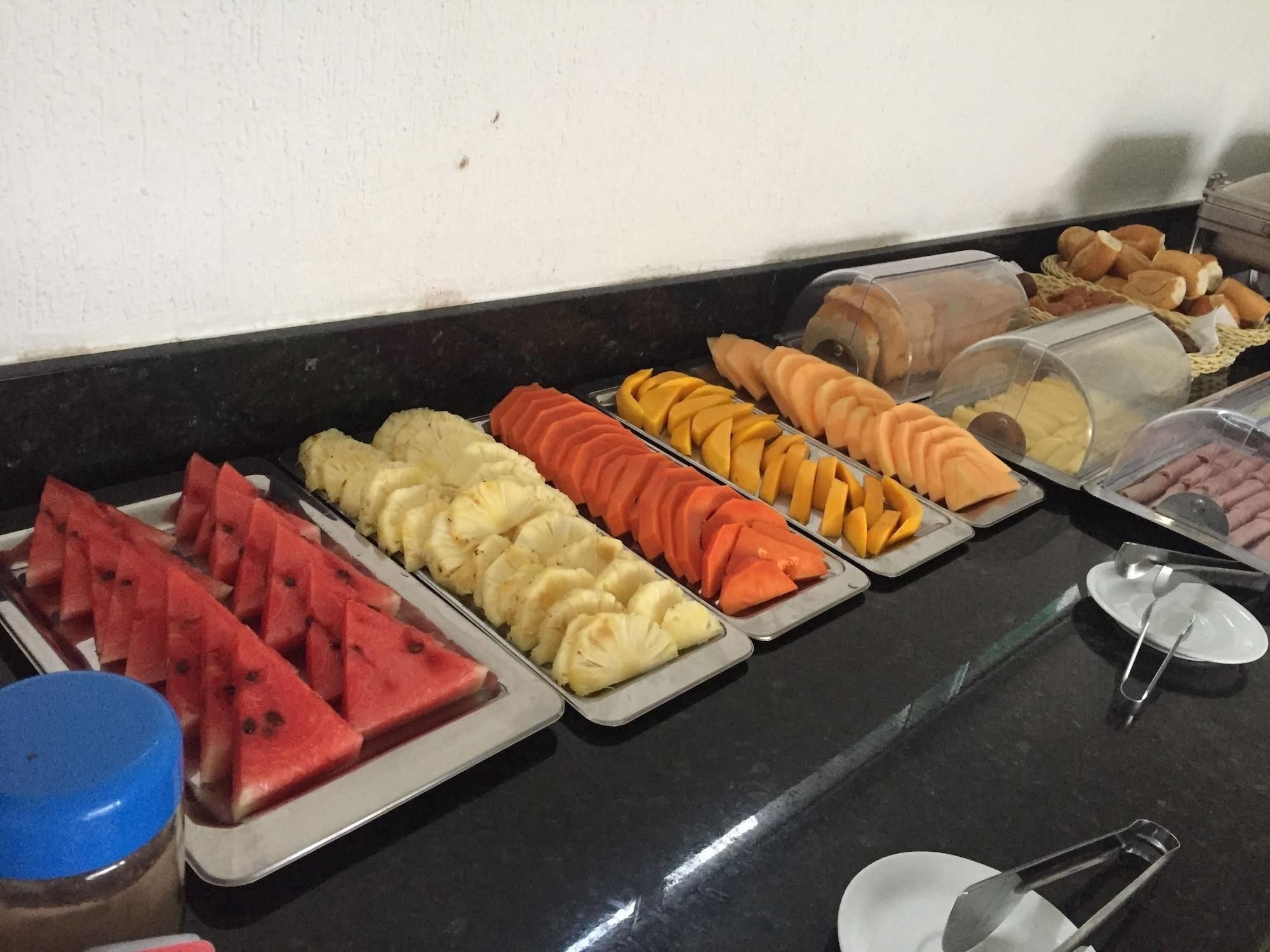 Un bufé con diversas frutas y productos de pastelería.