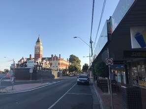 A street view with a historic building featuring a clock tower, a Subway restaurant, and a no cycling sign.
