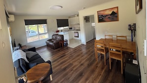 A compact living space with a kitchenette, a dining area, and a seating area with a sofa and a small table.