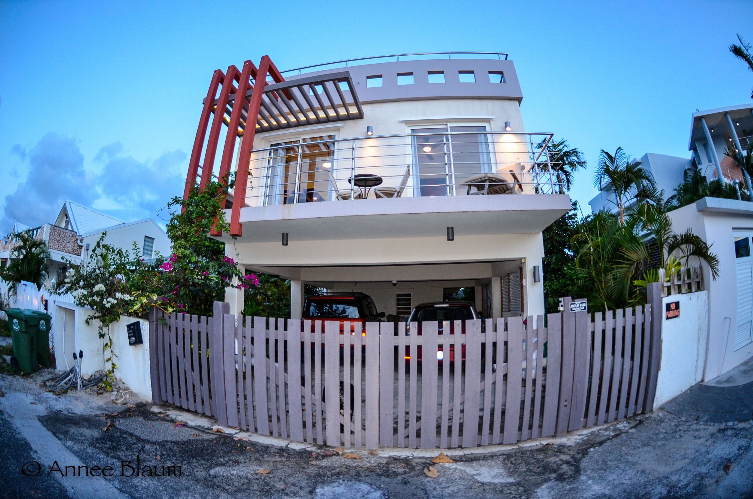 A modern two-story house with a balcony, a wooden fence, and a garage.