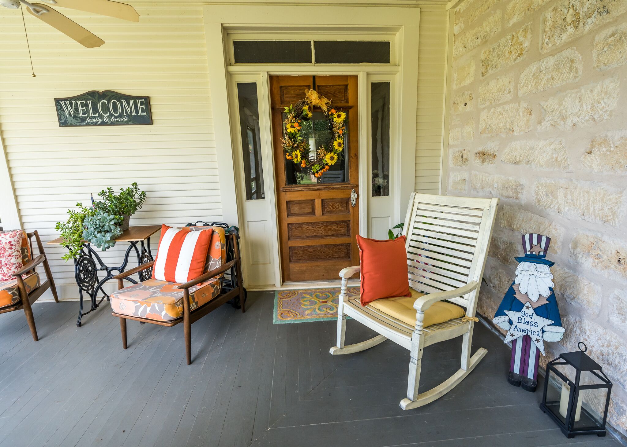 A porch with a rocking chair, a bench, and a welcome sign.