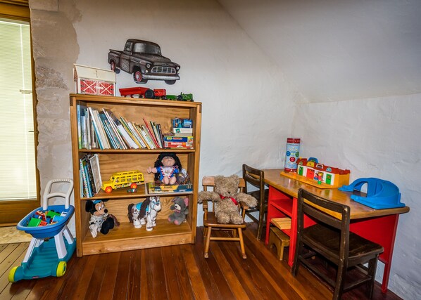 A child's playroom with a wooden bookshelf, toys, and a small table. - Secluded Farmhouse, vineyard on 4 acres, near wineries, shaded yard & EV charger (Fredericksburg)
