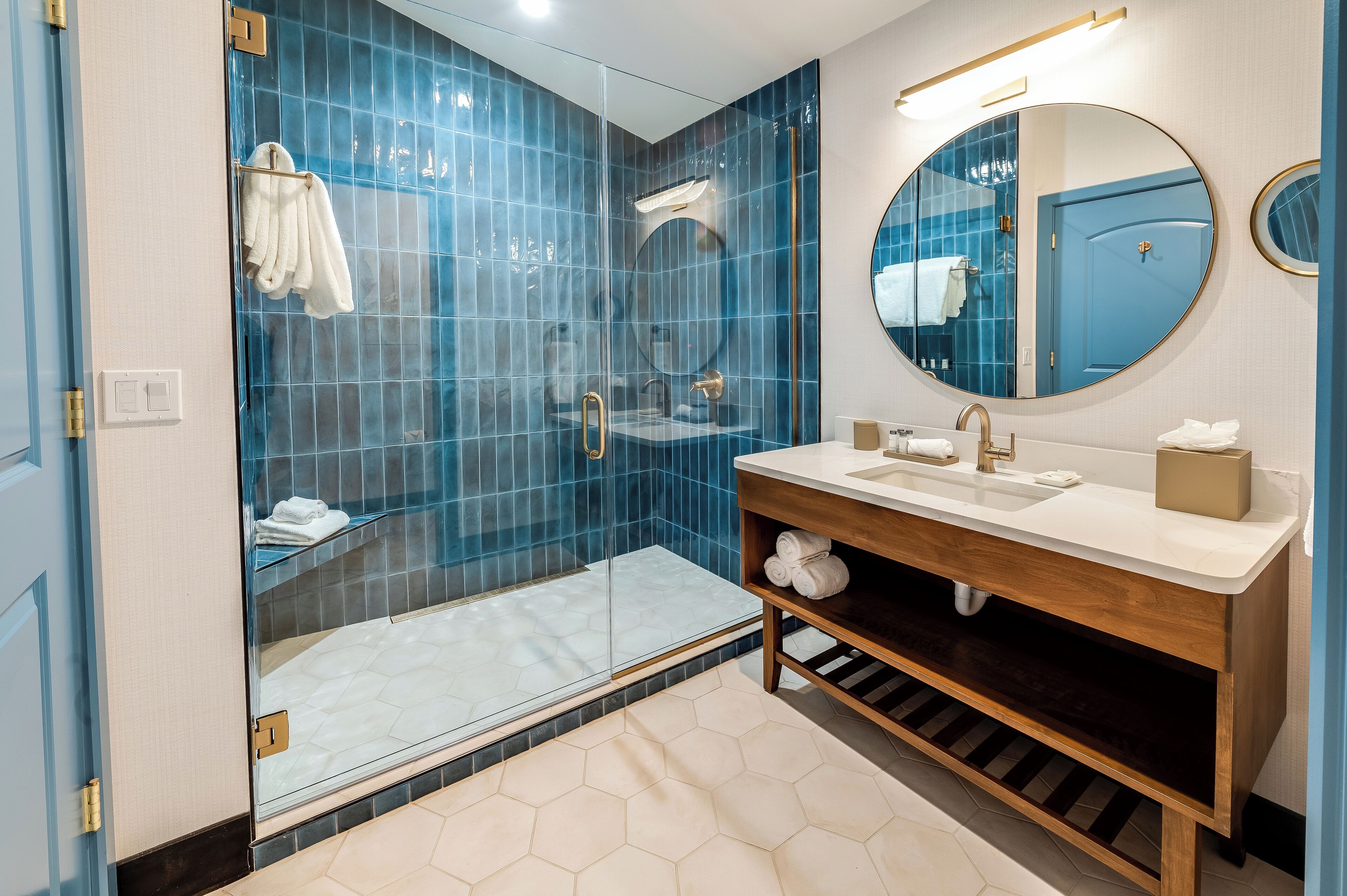 A modern bathroom with a glass-enclosed shower, a wooden vanity with a sink, and a large mirror.