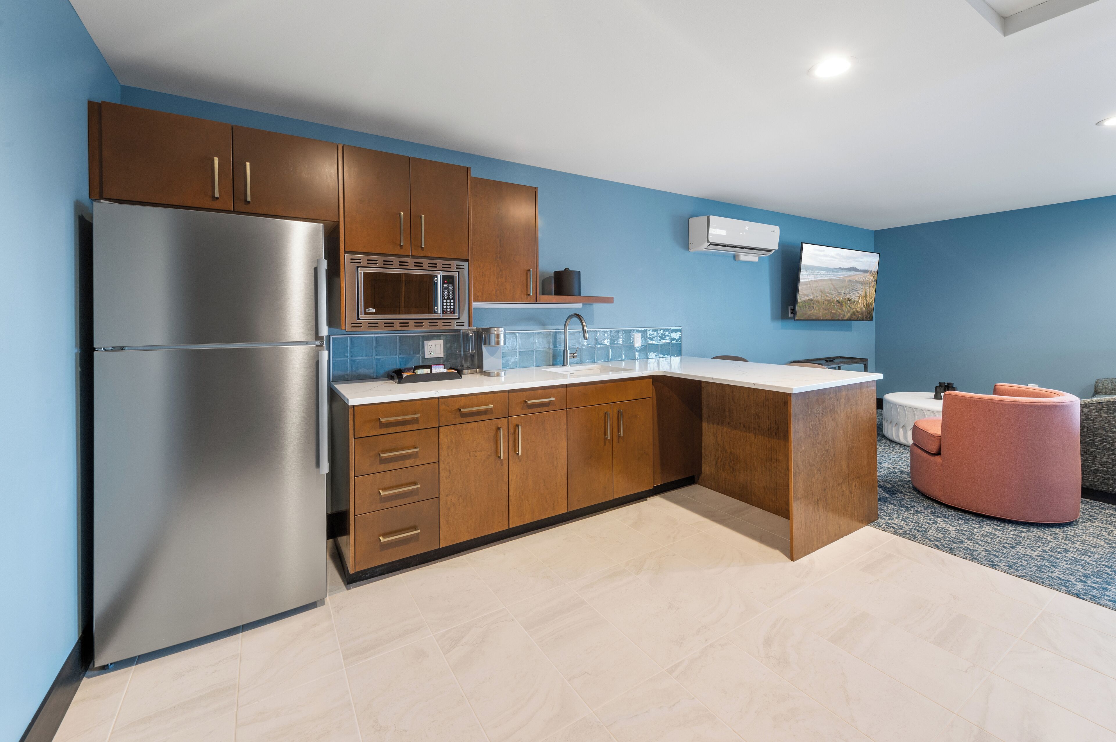 Una cocina moderna con armarios de madera, un refrigerador de acero inoxidable, un microondas y un fregadero.