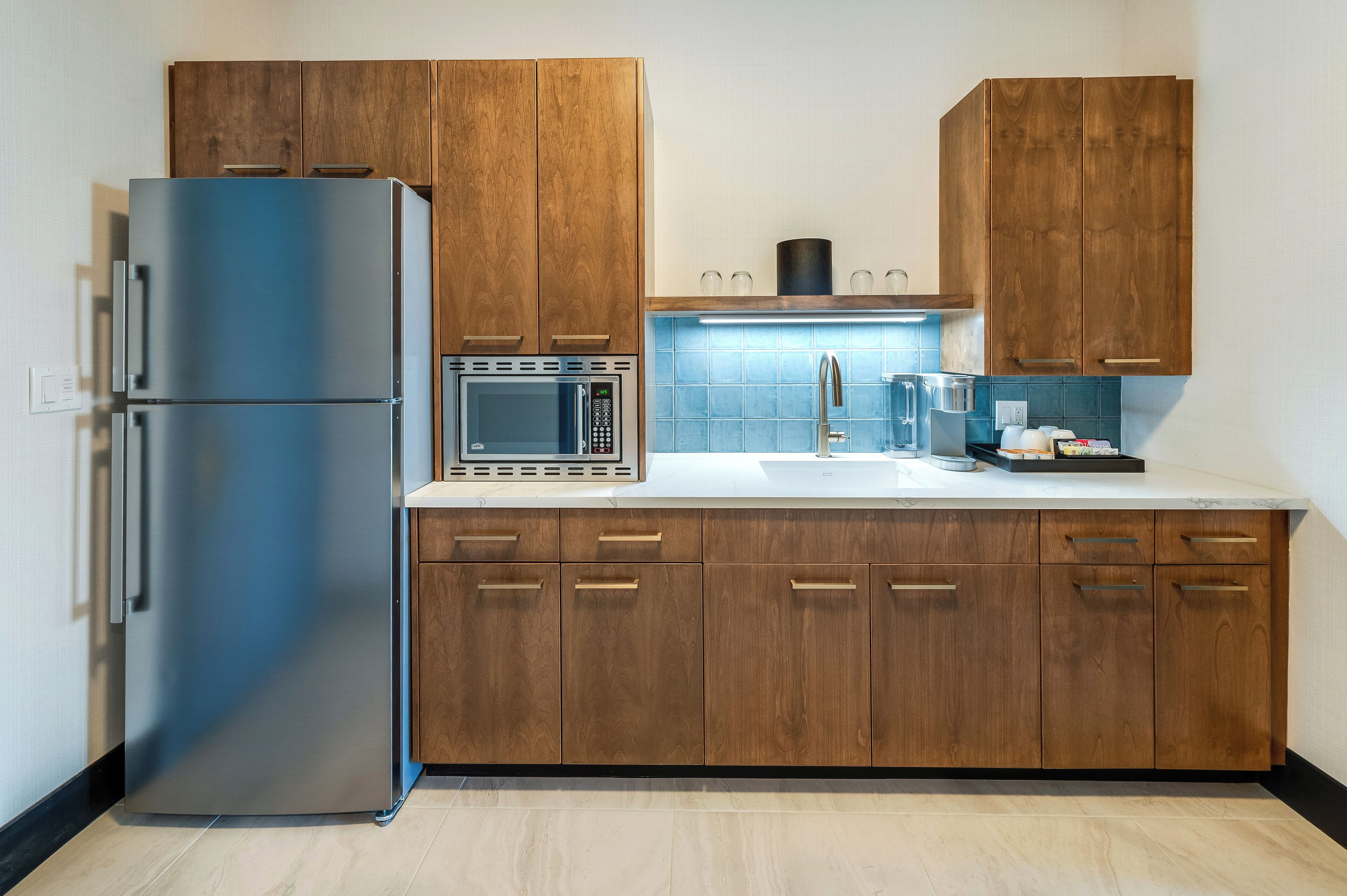 A modern kitchen with wooden cabinets, stainless steel appliances, and a marble countertop.