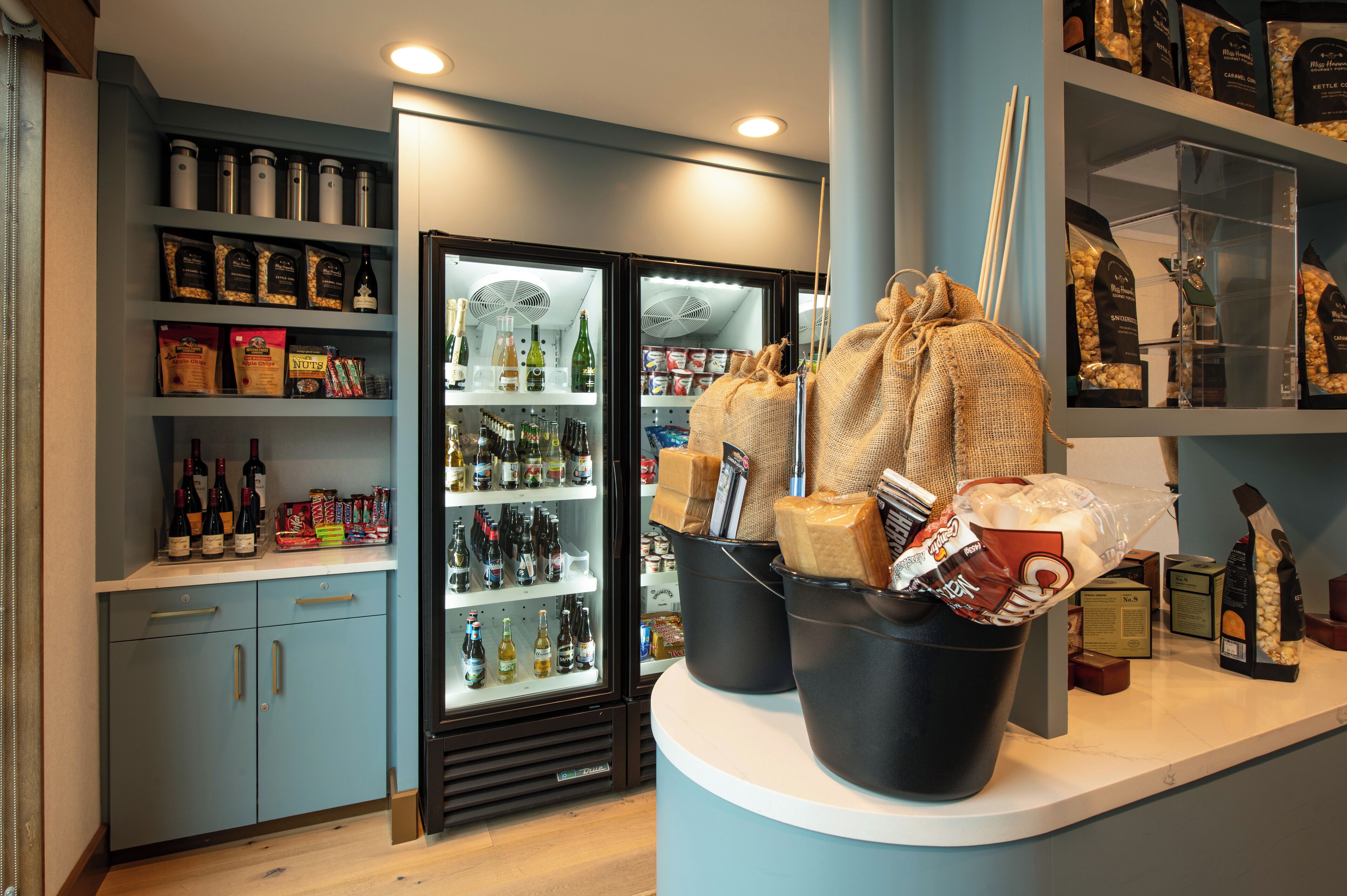A kitchen area with a refrigerator stocked with beverages, a sink, and various food items on the counter.