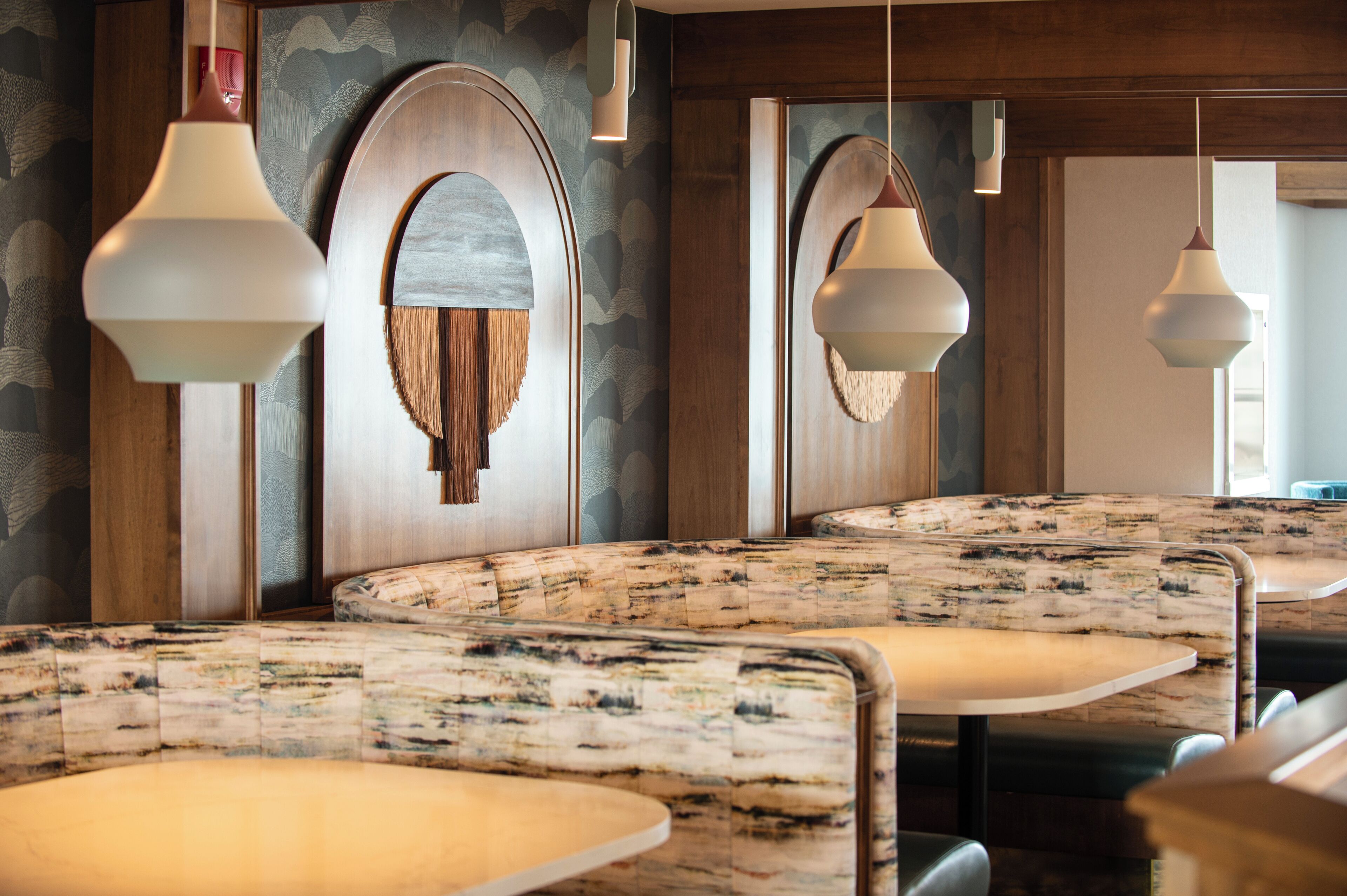 A restaurant interior with booth seating, wooden paneling, and pendant lighting.