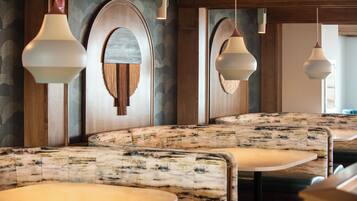 A restaurant interior with booth seating, wooden paneling, and pendant lighting.