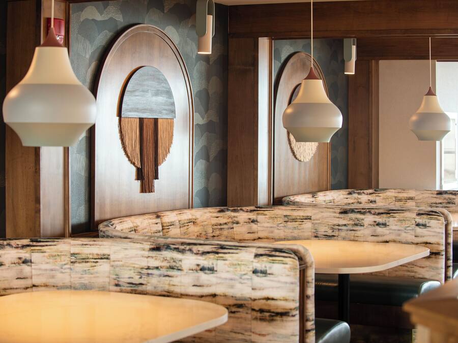 A restaurant interior with booth seating, wooden paneling, and pendant lighting.