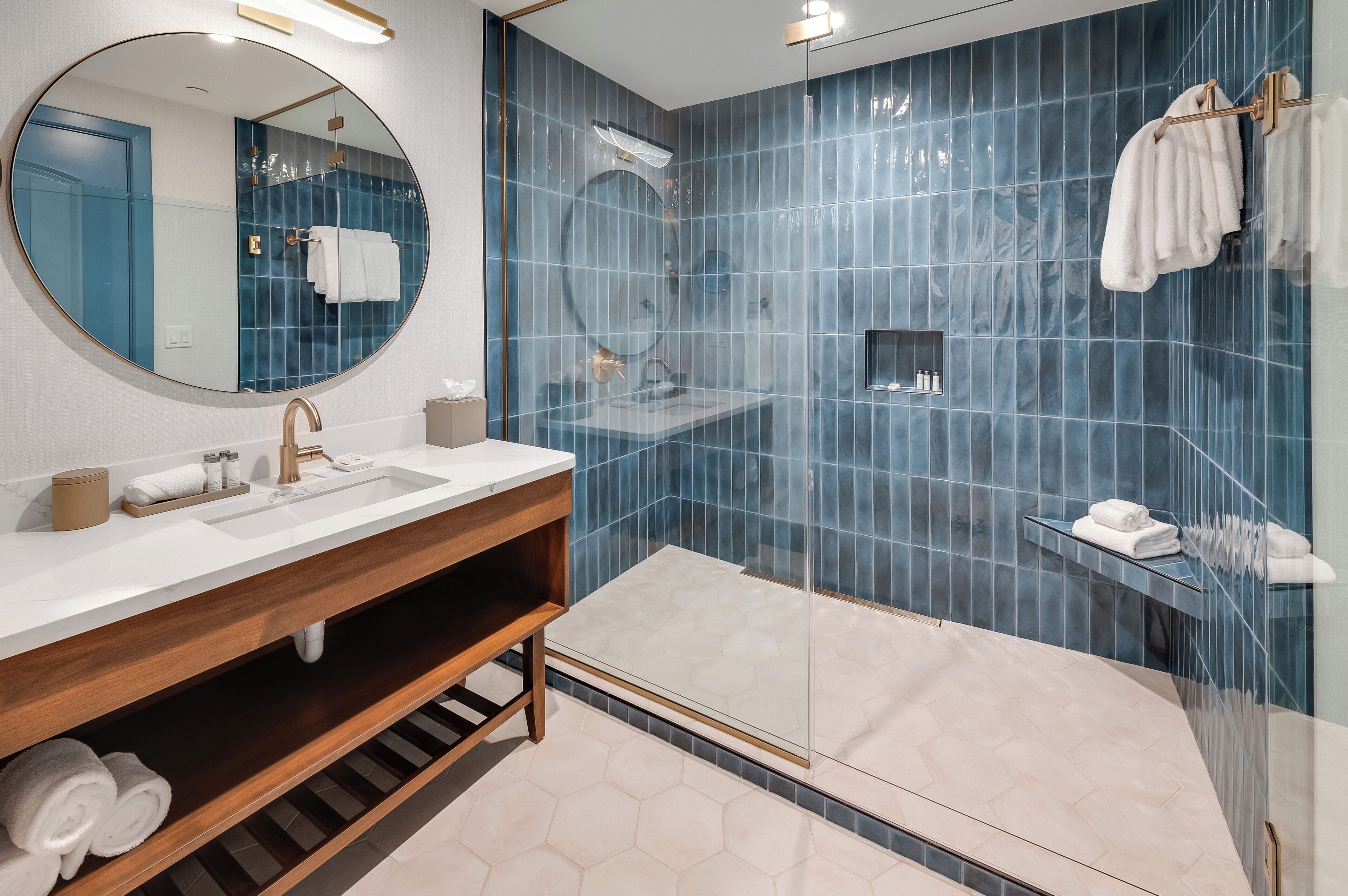 A modern bathroom with a large mirror, a sink, a glass-enclosed shower, and a wooden vanity.