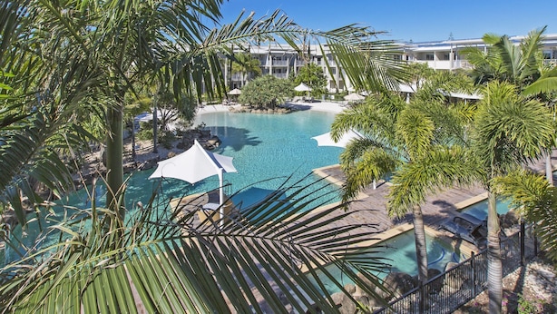 A resort with a large pool surrounded by palm trees and a building with balconies. - Resort & Spa 6316 withTropical Pool Views - 230m to Beach (KINGSCLIFF)