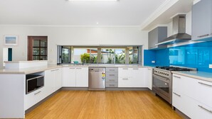 A modern kitchen with white cabinetry, a stainless steel dishwasher, a built-in oven, and a blue backsplash.