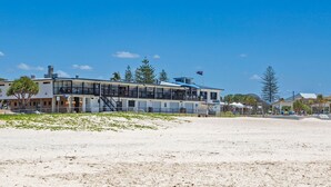 A beachfront building with multiple levels, a balcony, and a flag.
