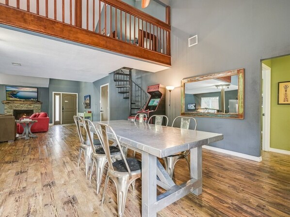 A spacious dining area with a high ceiling and a staircase leading to an upper level. - Great Pool House with Modern Design Touches! (Austin)